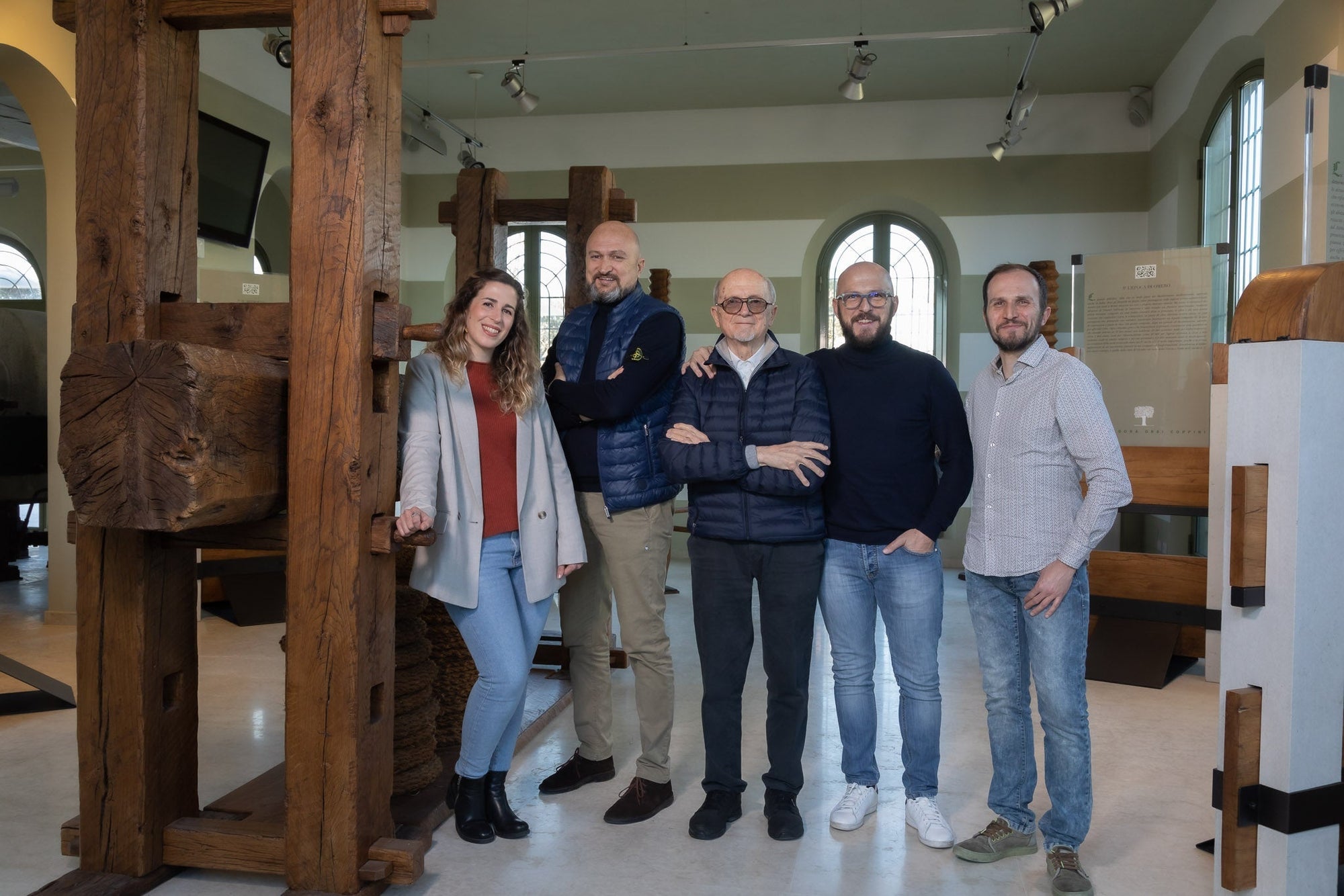Foto della famiglia Coppini. Anita, Matteo, Ernesto, Francesco, Gigi nella sala museale con macchinari per la produzione dell'olio del 1600.  